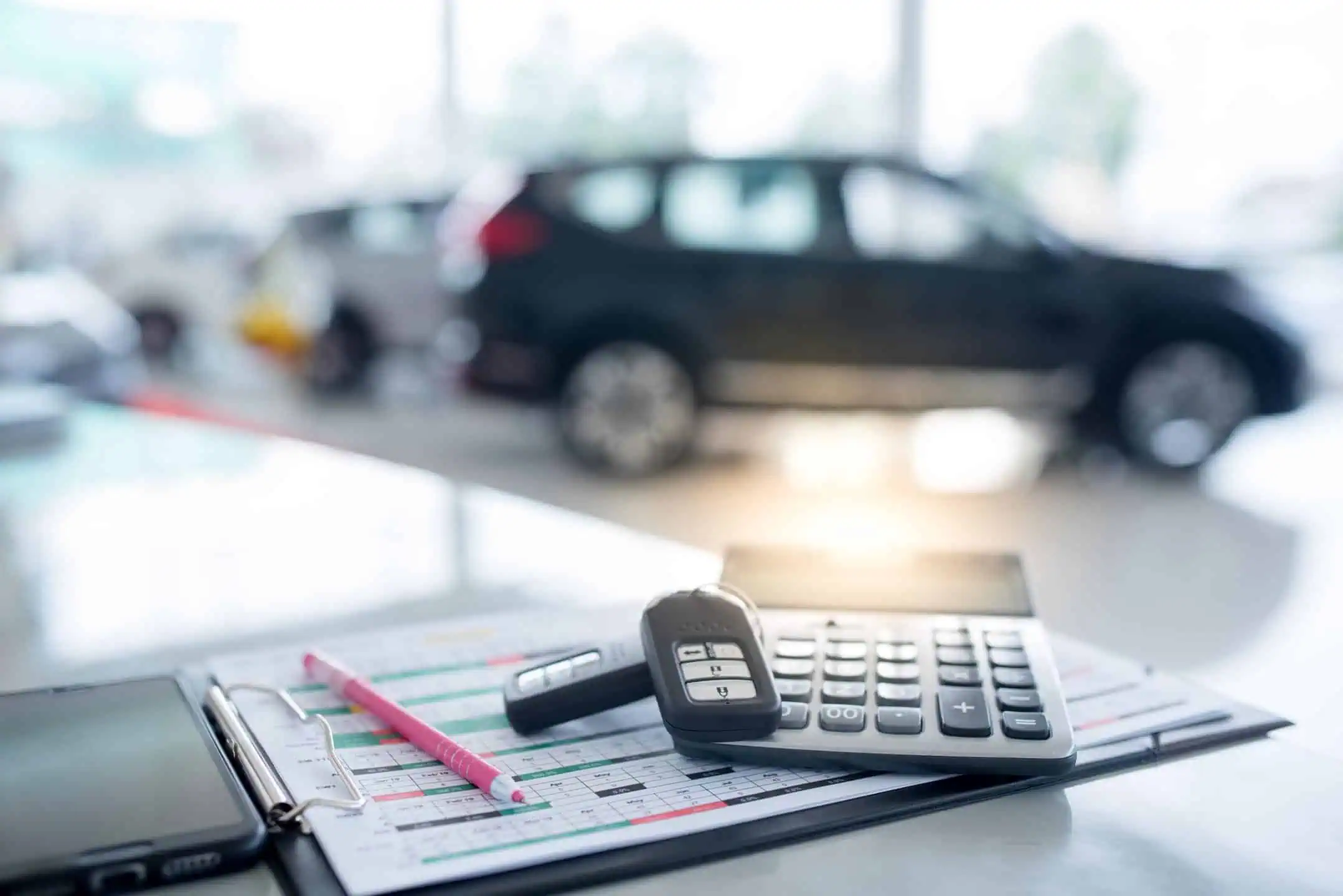 Car Keys Calculator And Pen Infron Of Out Of Focus Car In Showroom