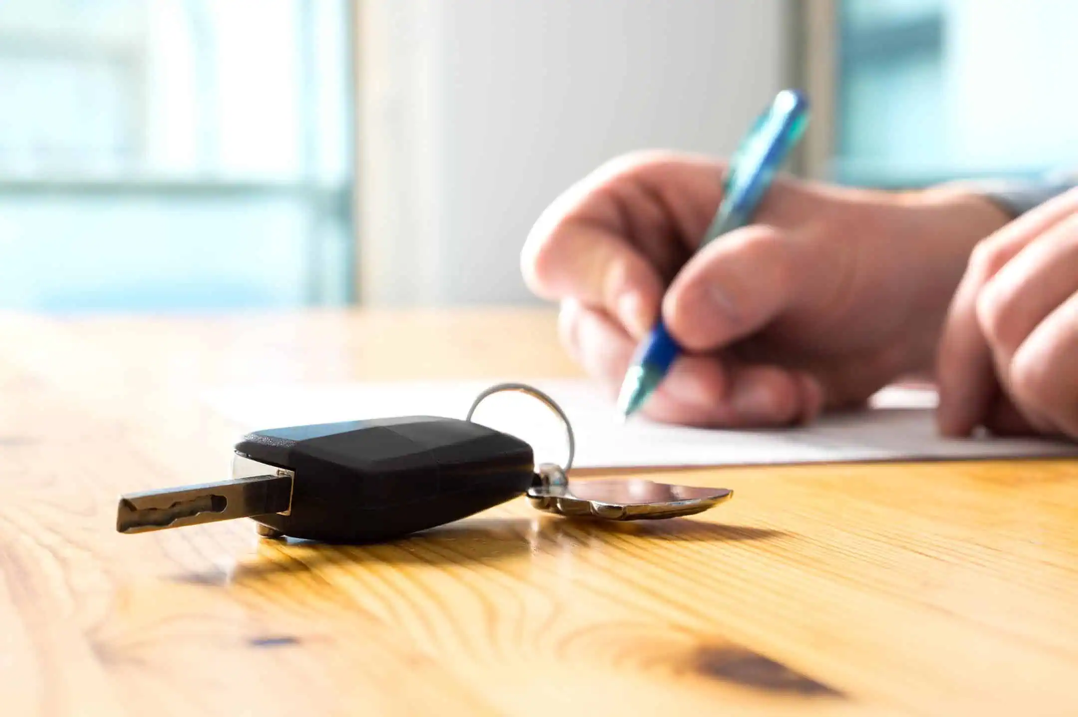 Car Keys With Man Signing Agreement Behind