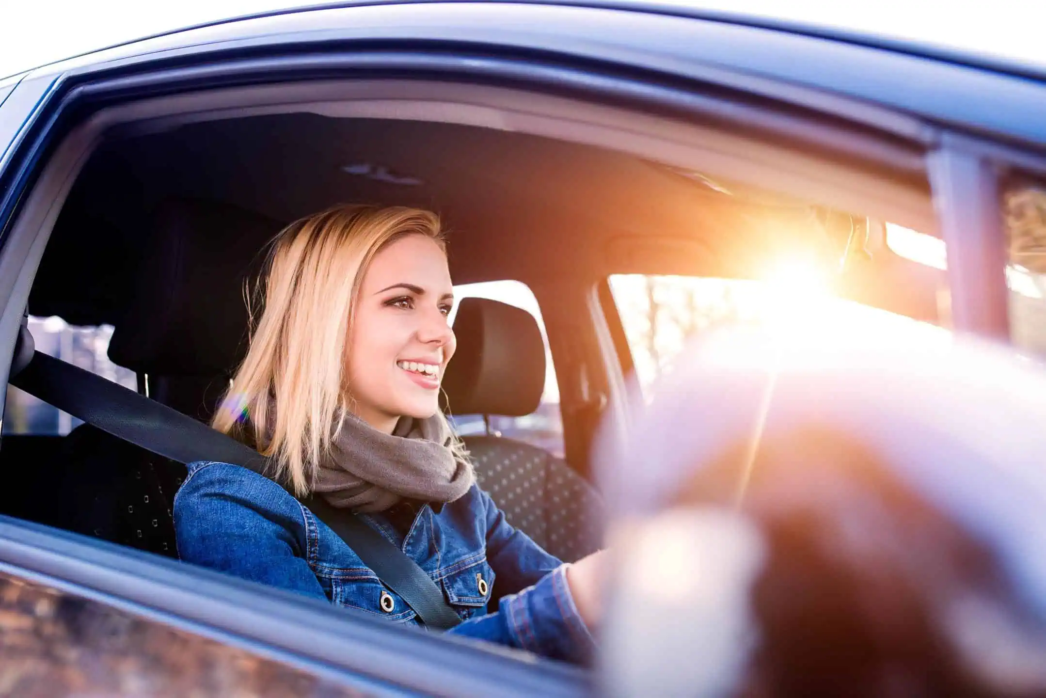 Girl In Denim Jacket Smiling A Driving A Blue Car