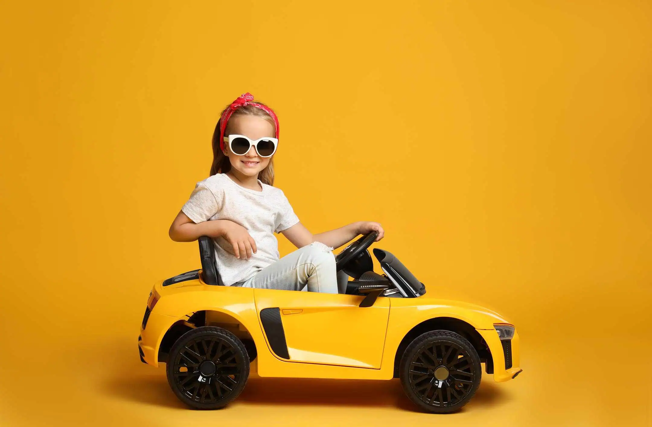 Girl In Toy Car Yellow Background