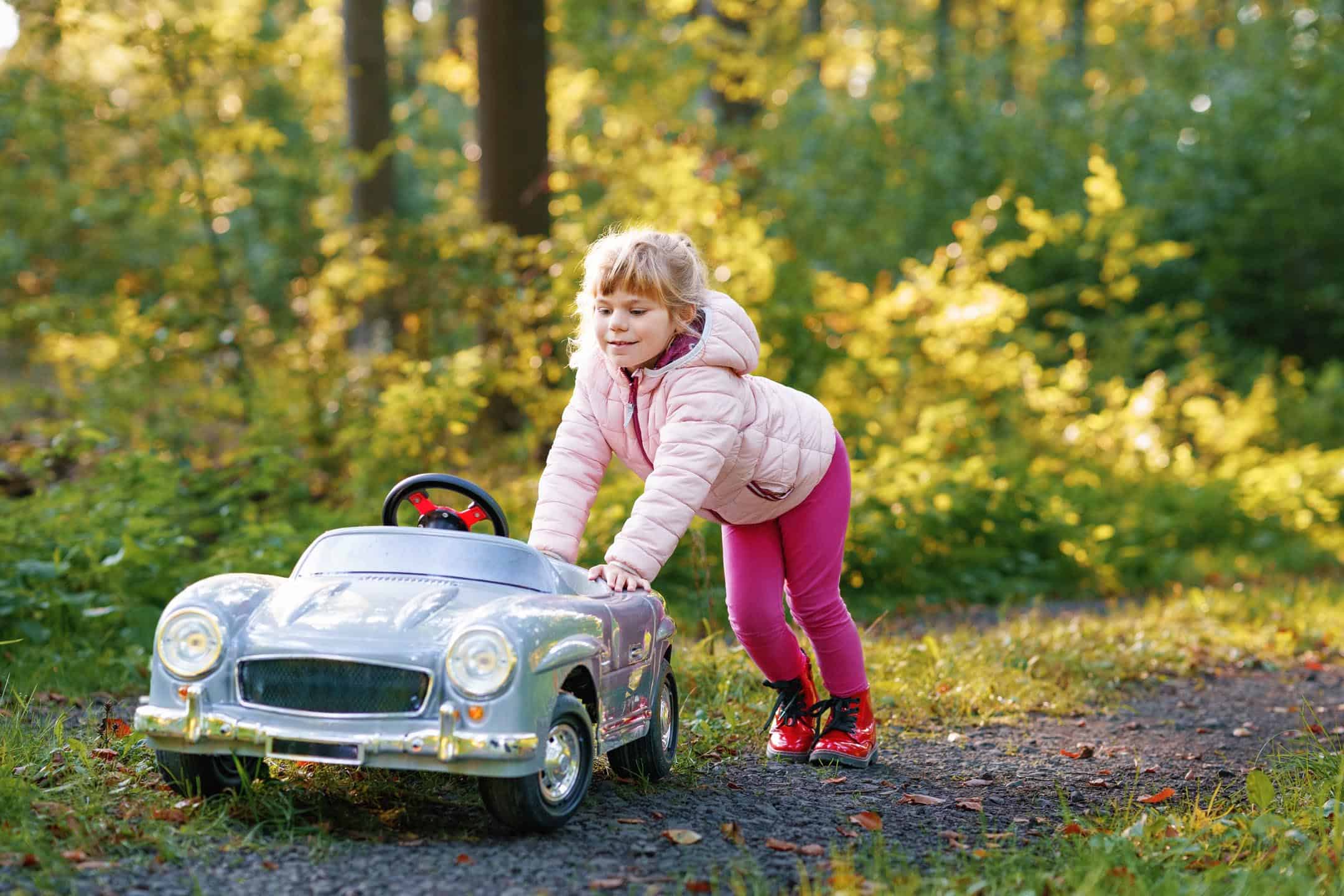 Lifestyle Young Girl Pushing A Toy Car Outside