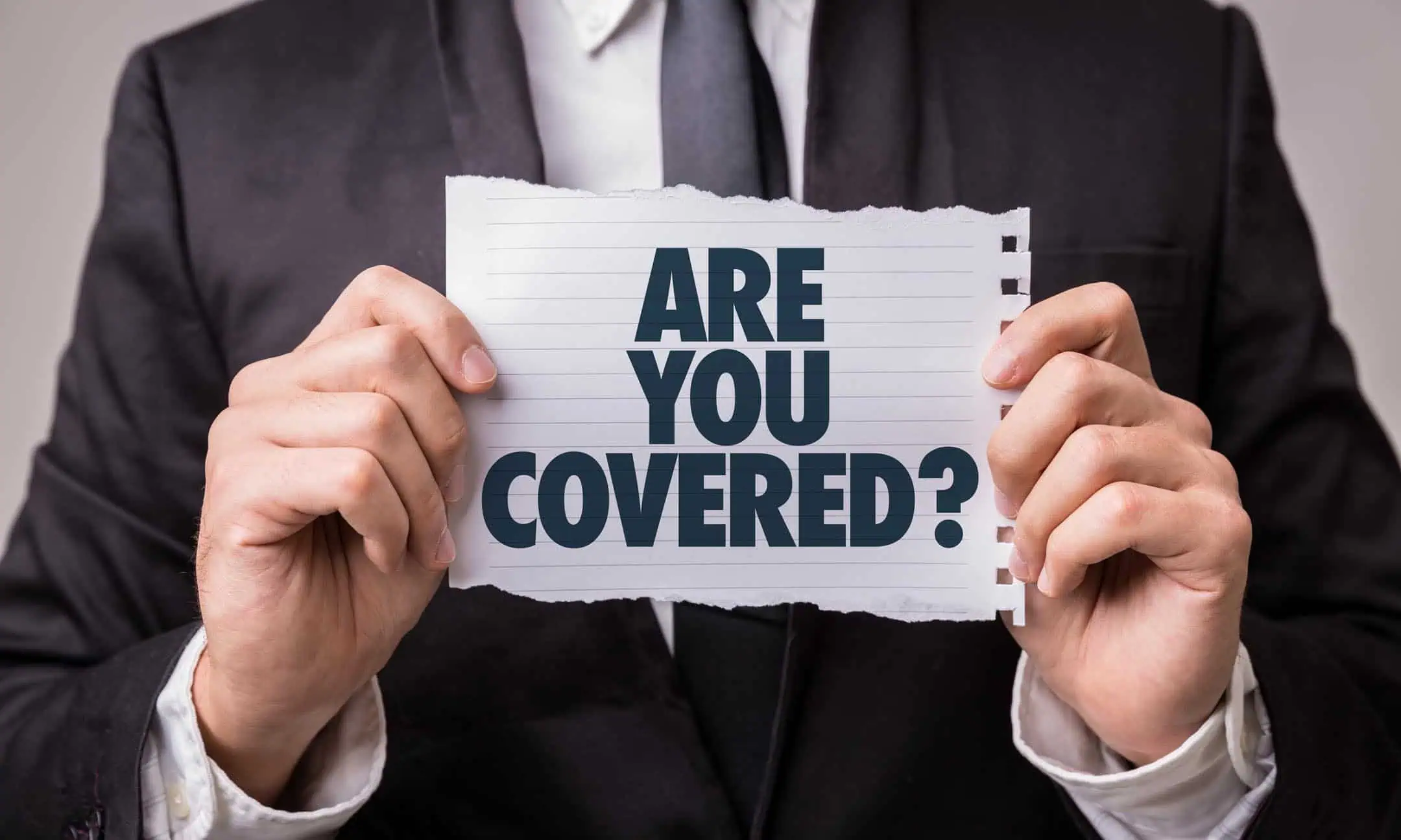 Man Holding Paper With Are You Covered On It