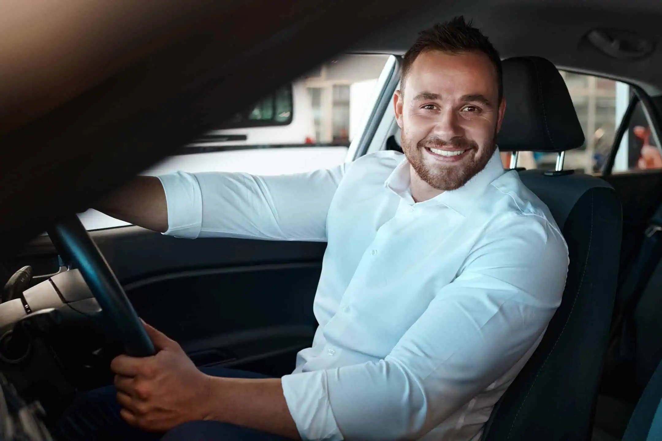 Man In Drivers Seat Looking Directly At Camera Smiling