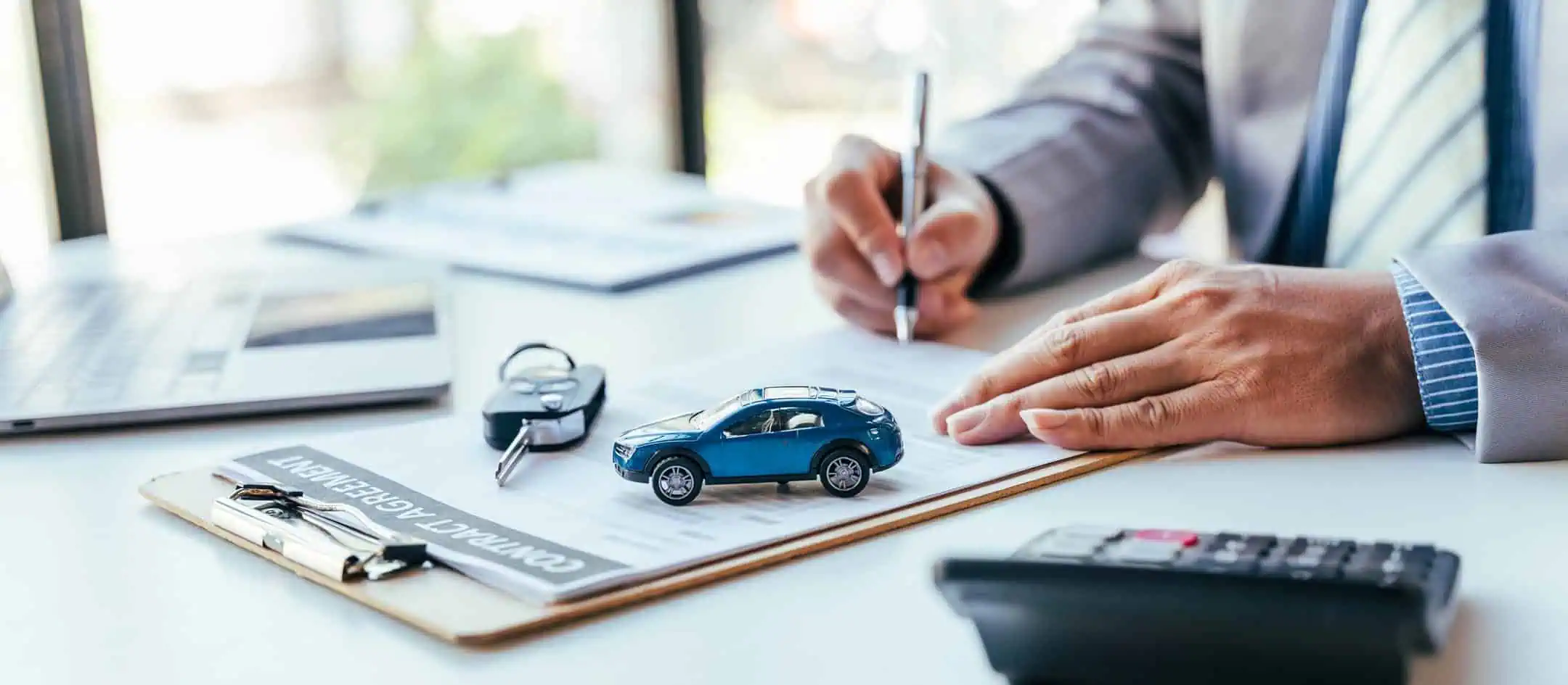 Man Signing Agreement Paperwork With Calculator Blue Toy Car And Keys