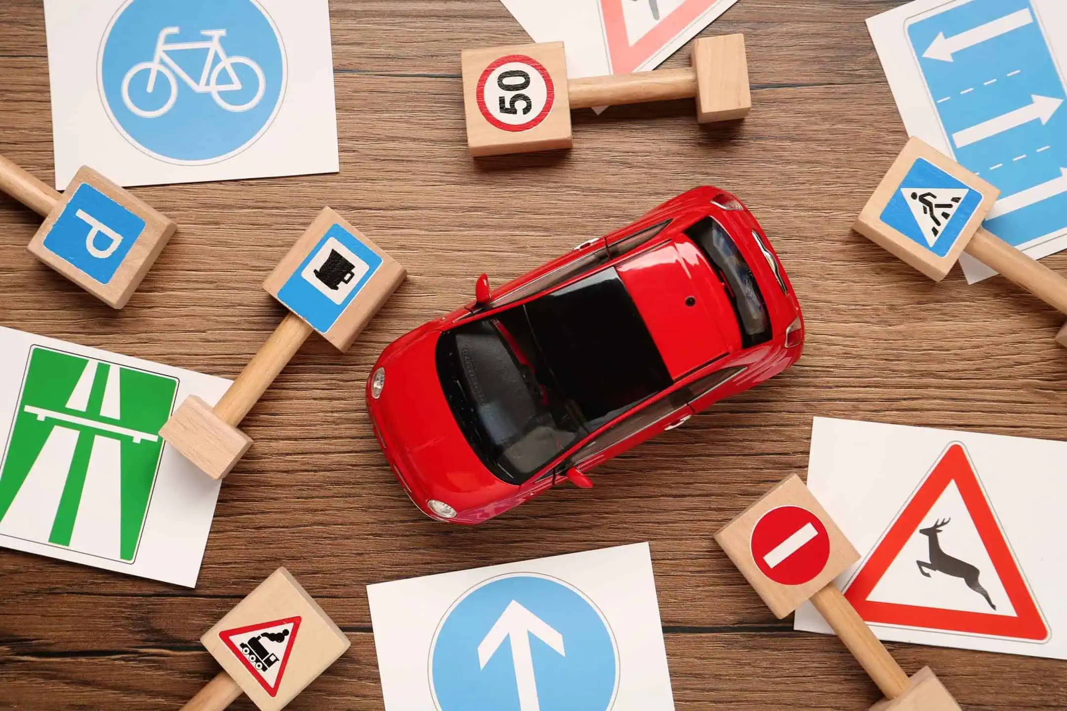 Red Toy Car On A Table Surrounded By Toy Road Signs