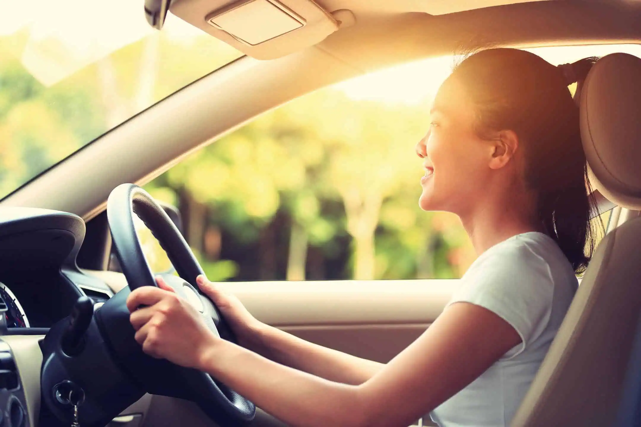 Smiling Girl Driving With Sun Shining Behind Her