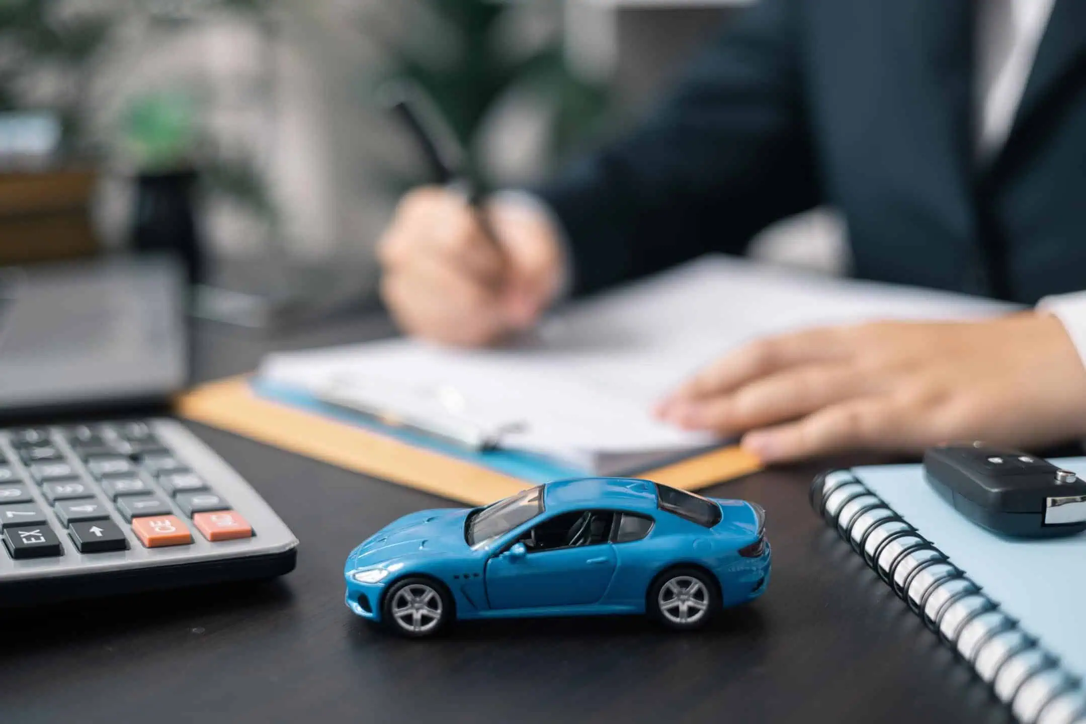 Toy Car In Front Of Man Signing Paperwork