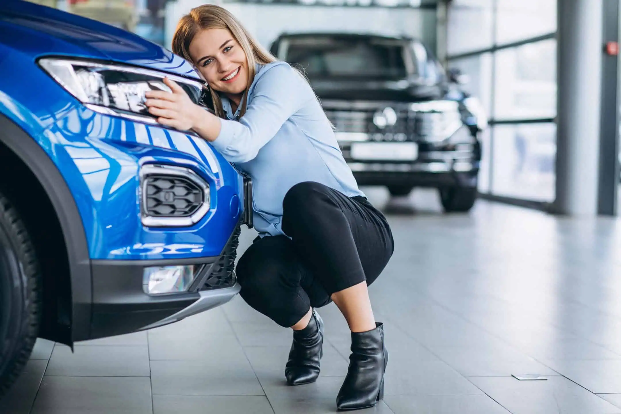 Woman Hufgging Front Of Blue Car In Showroom