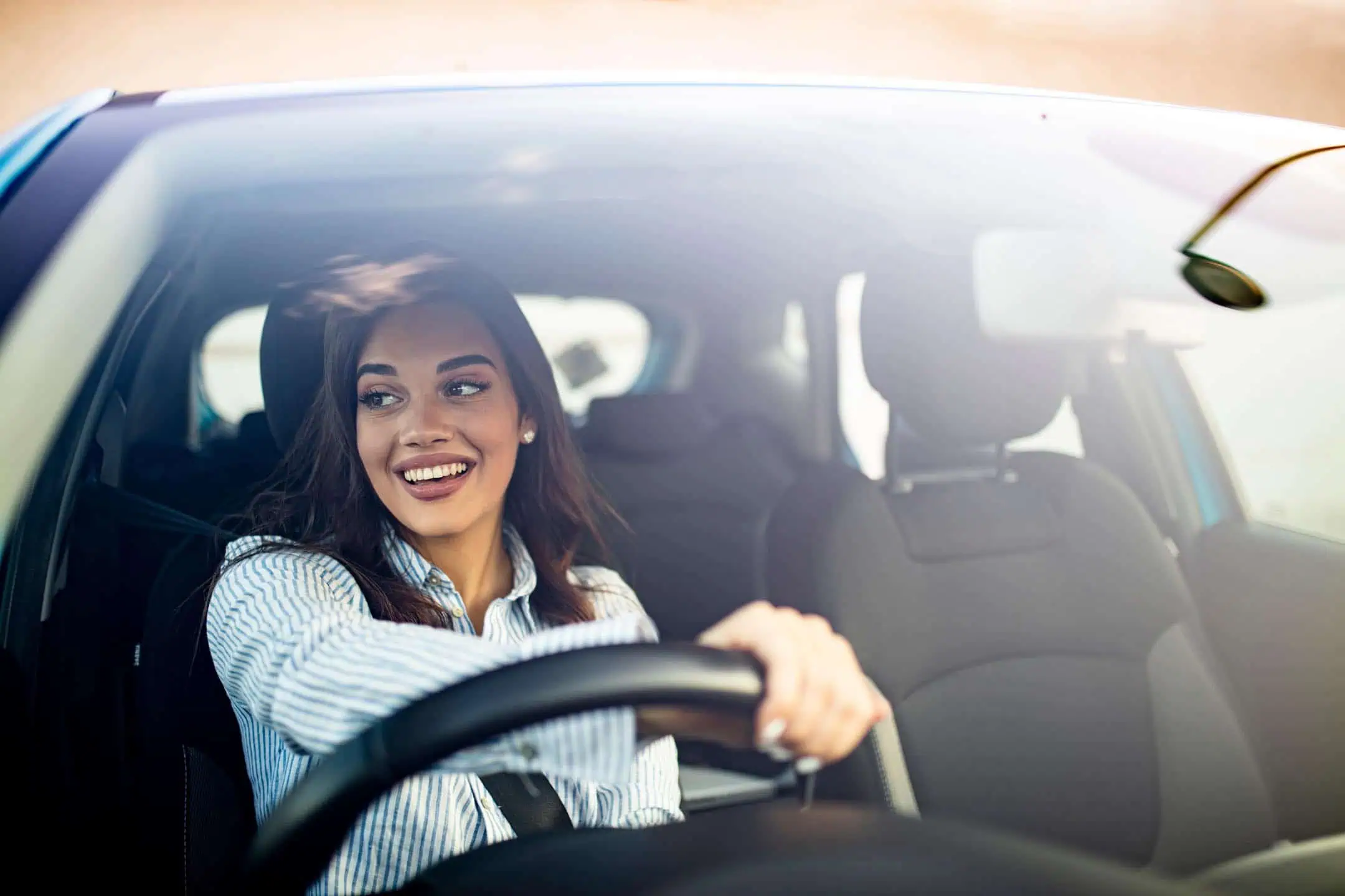 Young Woman Holding Wheel Smiling Looking Out Of Window